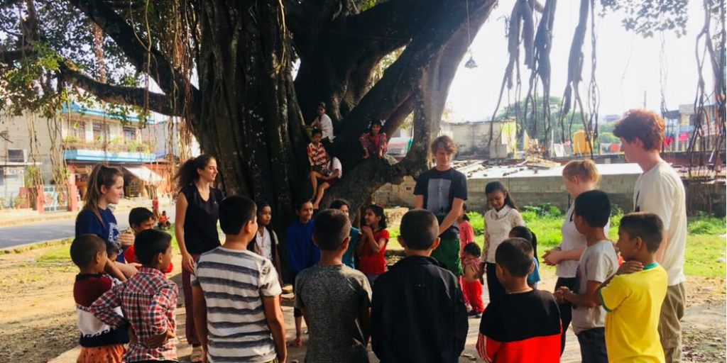 Childrn fra Pokhara samles under et stort tre med frivillige FRA GVI.