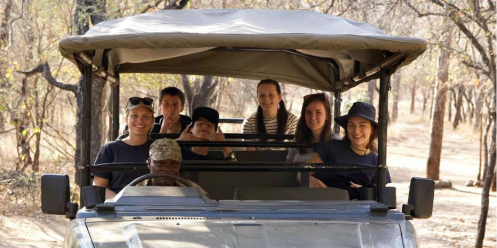 Voluntarios en un vehículo safari con un guardabosques en Limpopo.
